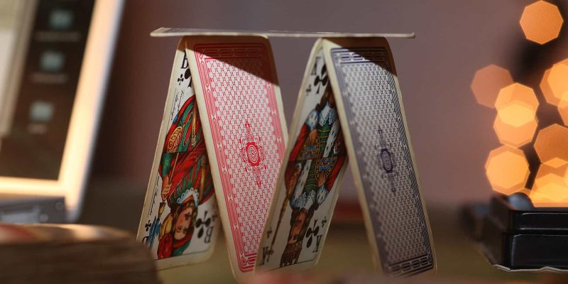 A house of cards on a desk representing mental game in online poker.